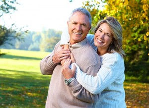 a women back hugging a man outside in the field while smiling