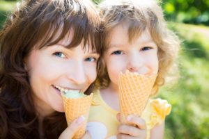 A woman enjoys ice cream with a complete smile with her daughter