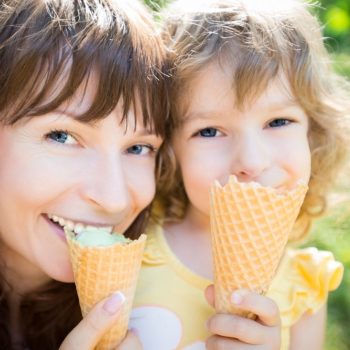 A woman enjoys ice cream with a complete smile with her daughter